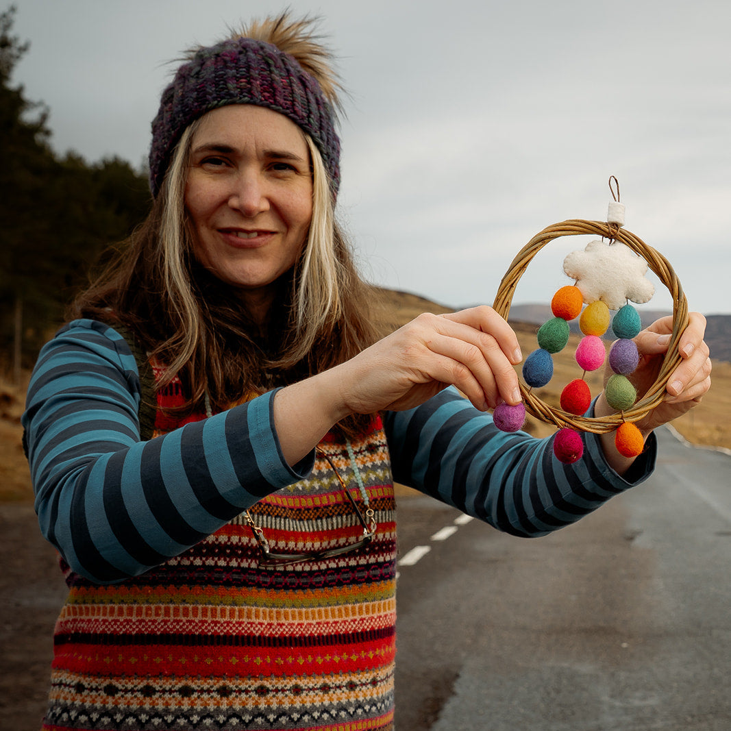 Person holding a colorful hanging ornament outdoors
