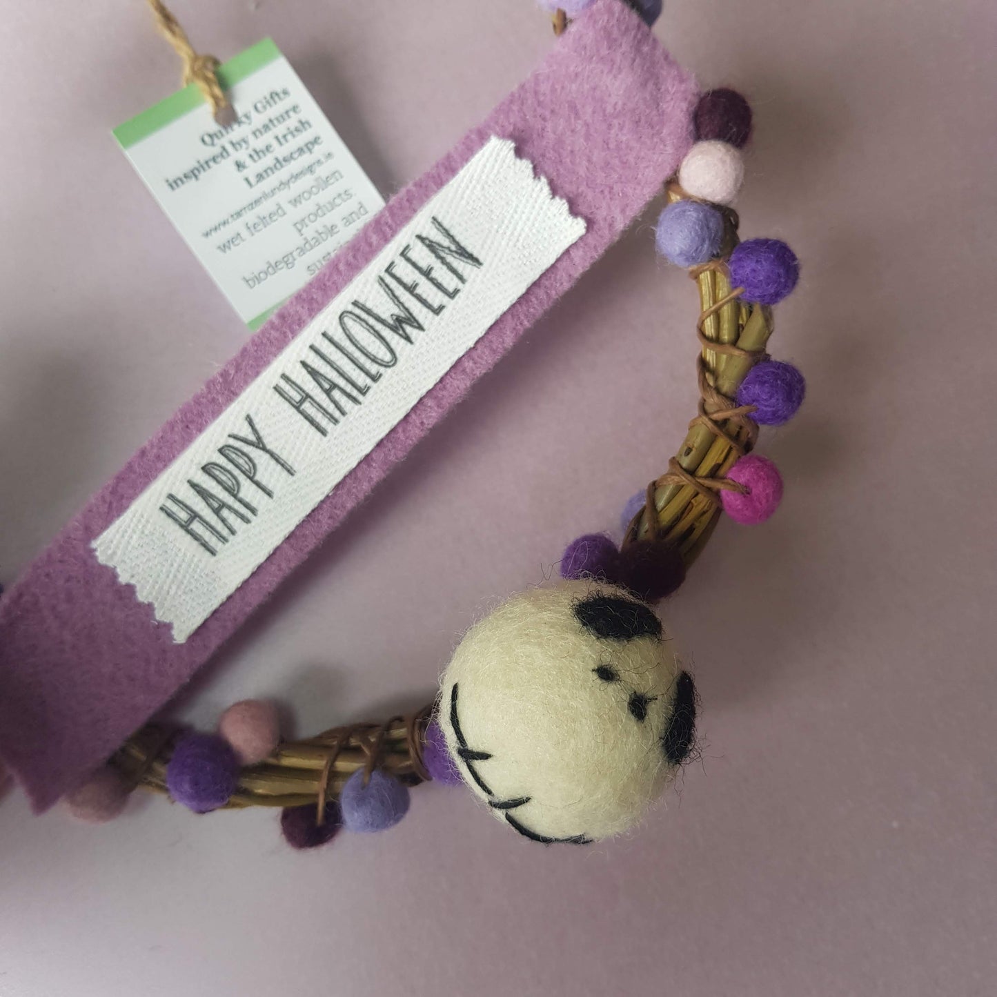 Decorative Halloween keychain with pom-poms and a tag on a plain background