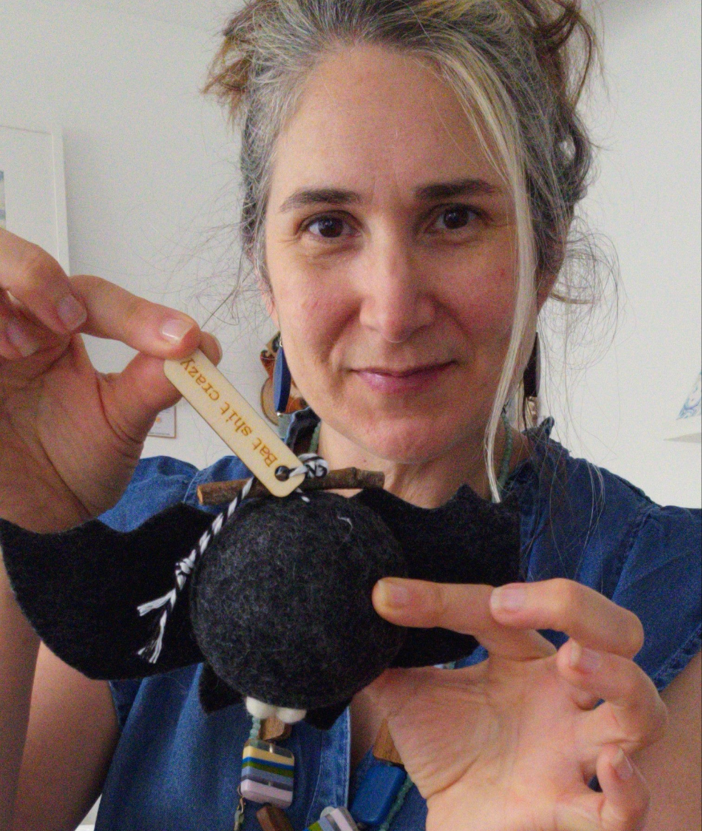 Person holding a small black felted object with a tag, wearing a blue shirt.