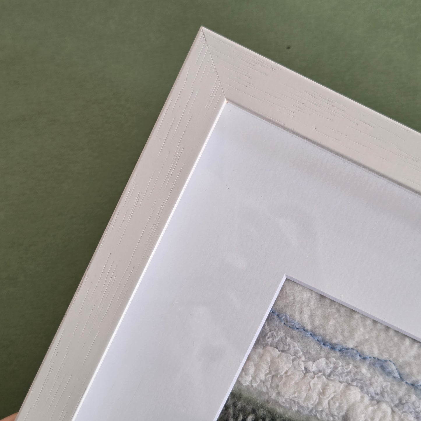 Close-up of a white picture frame corner on a green surface