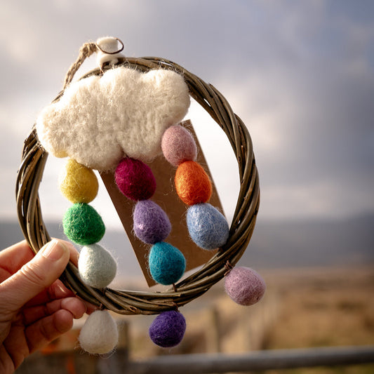Decorative ring with colorful pom-poms and a cloud-shaped object against a natural background