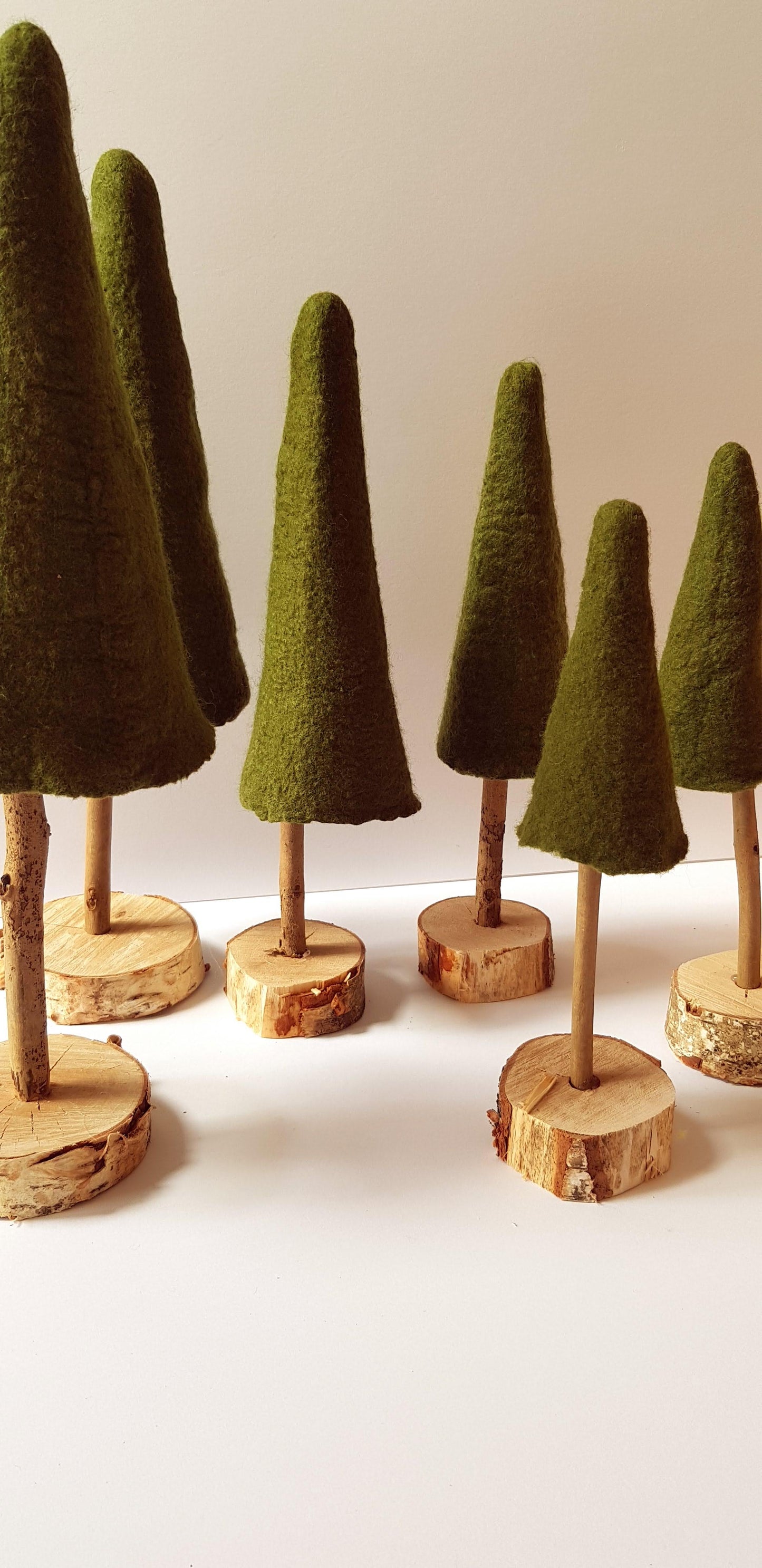 Set of green felt cones on wooden stands against a white background