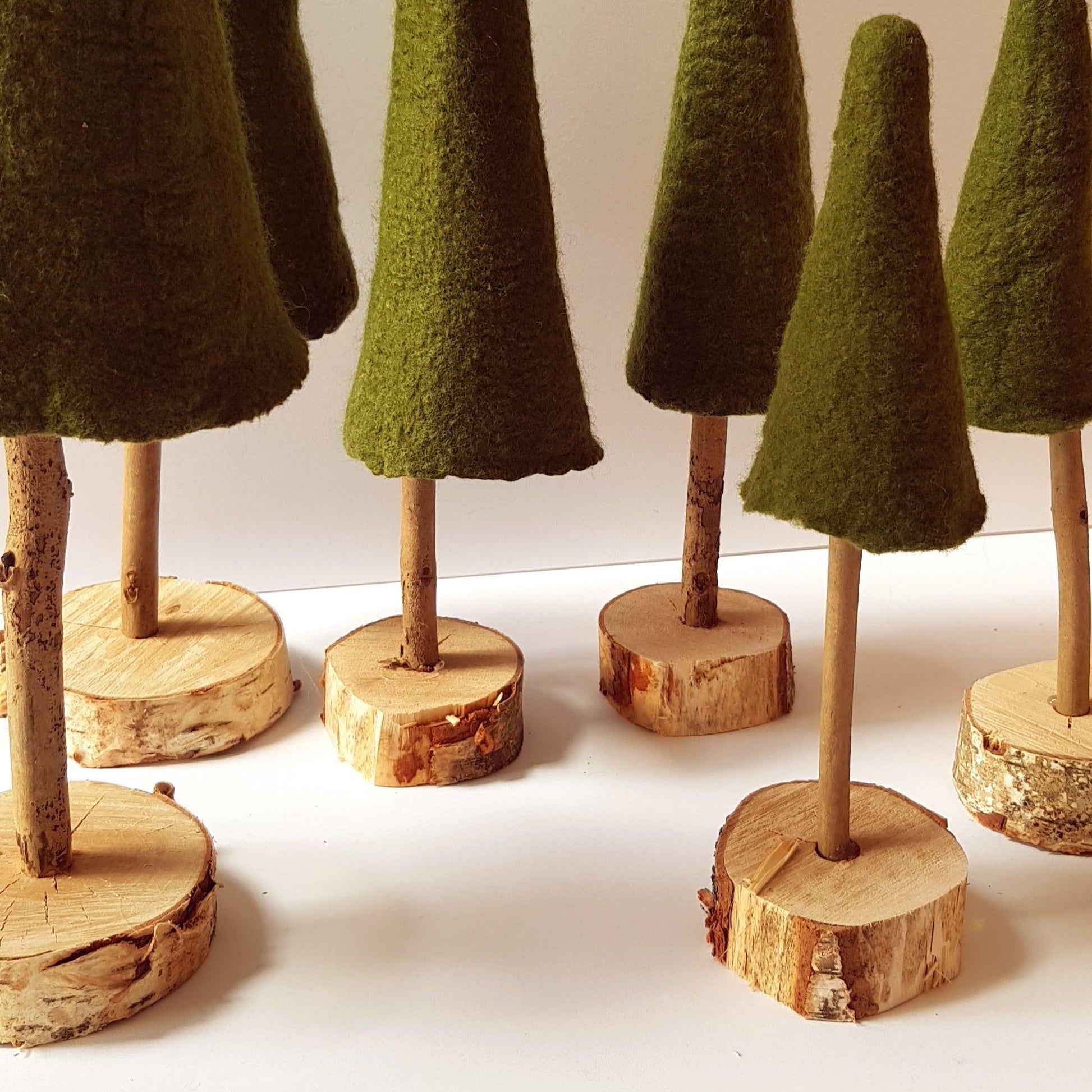 Set of green felt cones on wooden stands against a white background