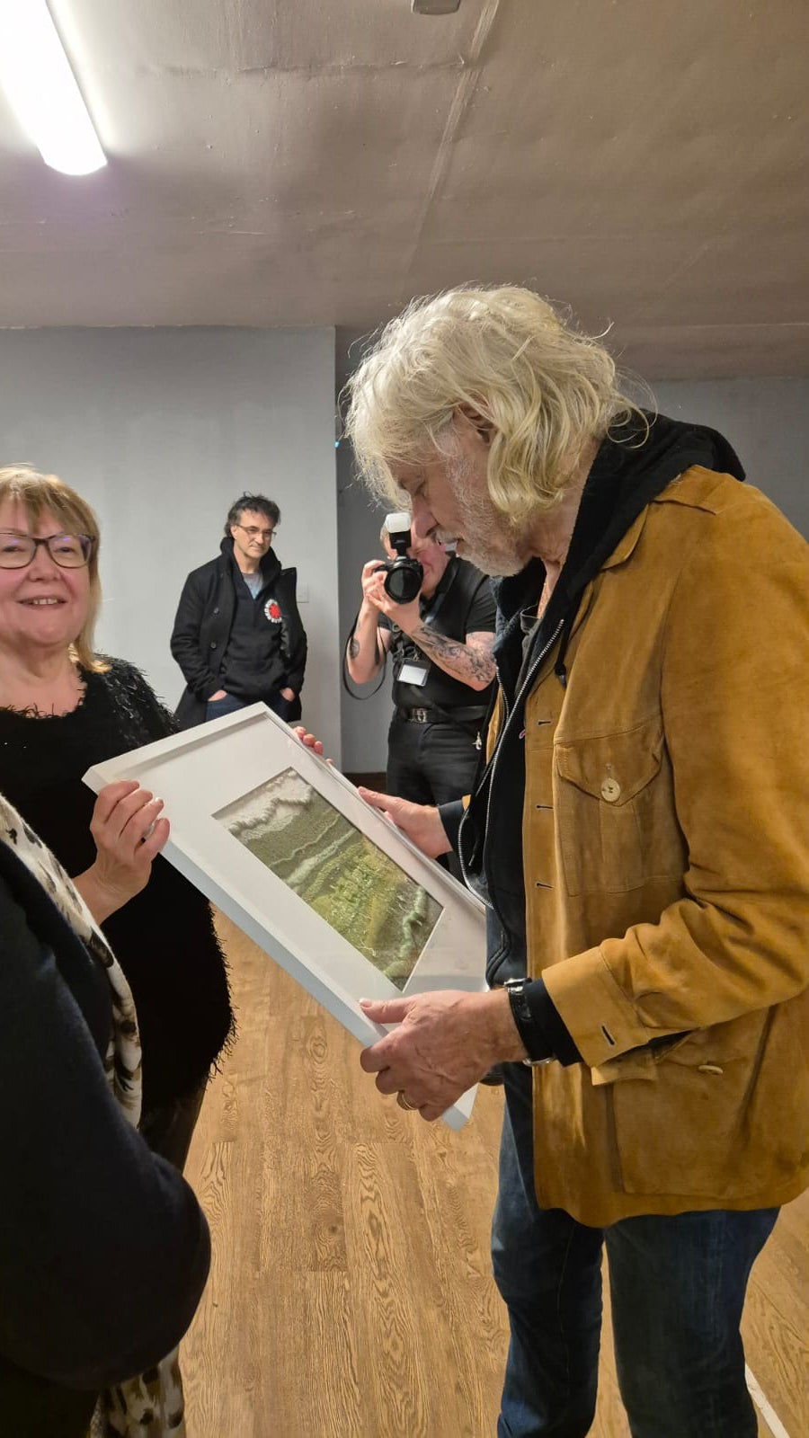 Woman holding a framed picture with Sir Bob Geldof. A gift of an original textile piece on behalf of Kildare County Council
