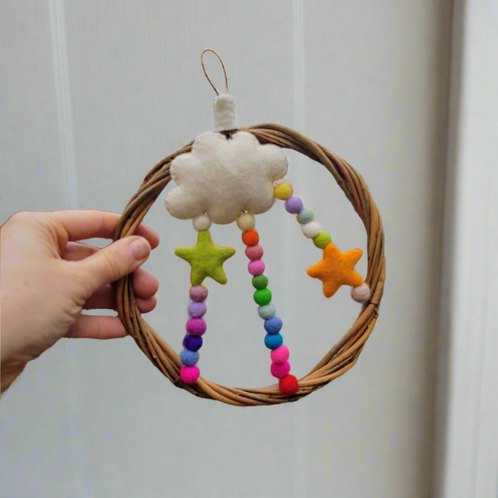Decorative ring with colorful beads and stars held by a hand against a natural background.