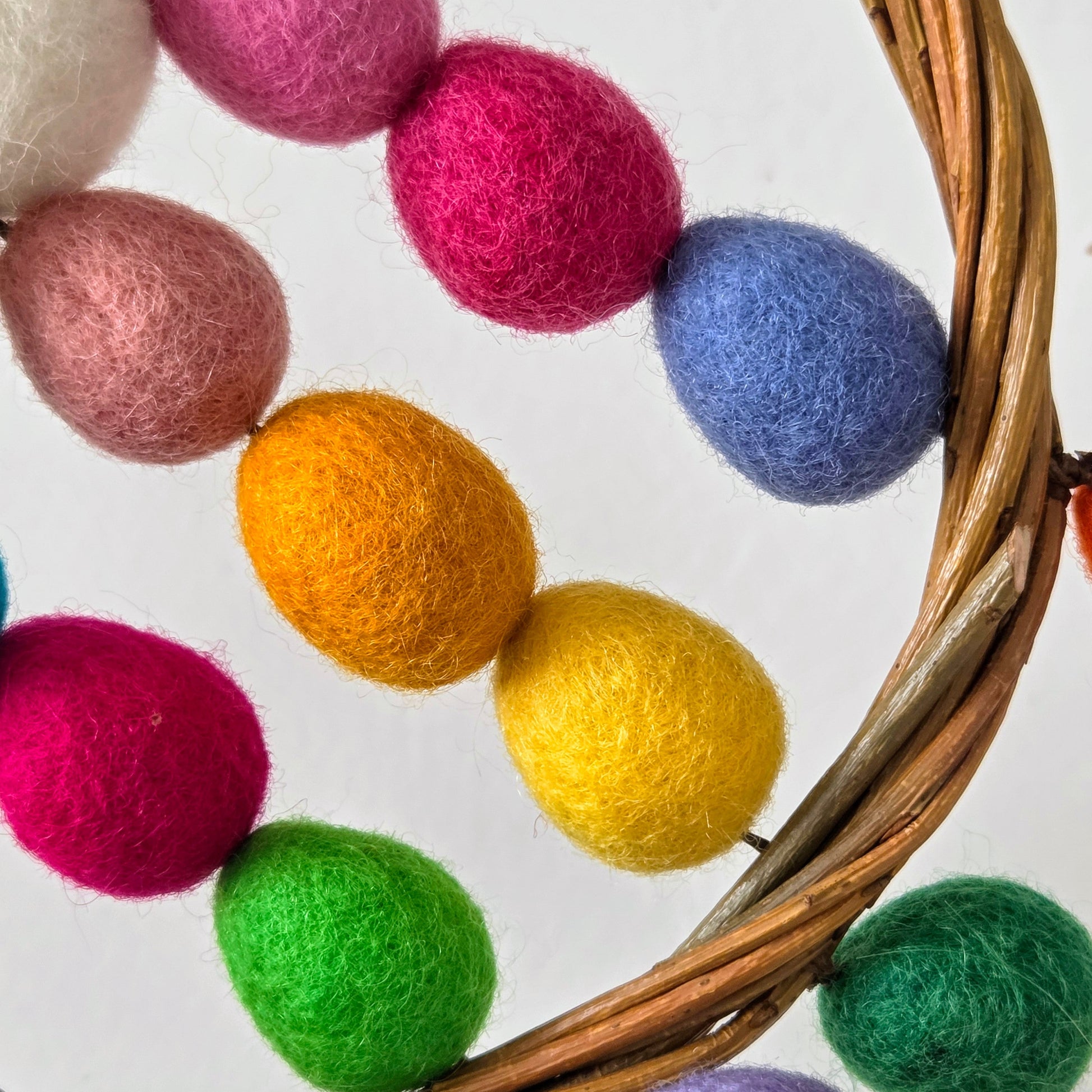 Colorful felt balls on a woven basket with a white background
