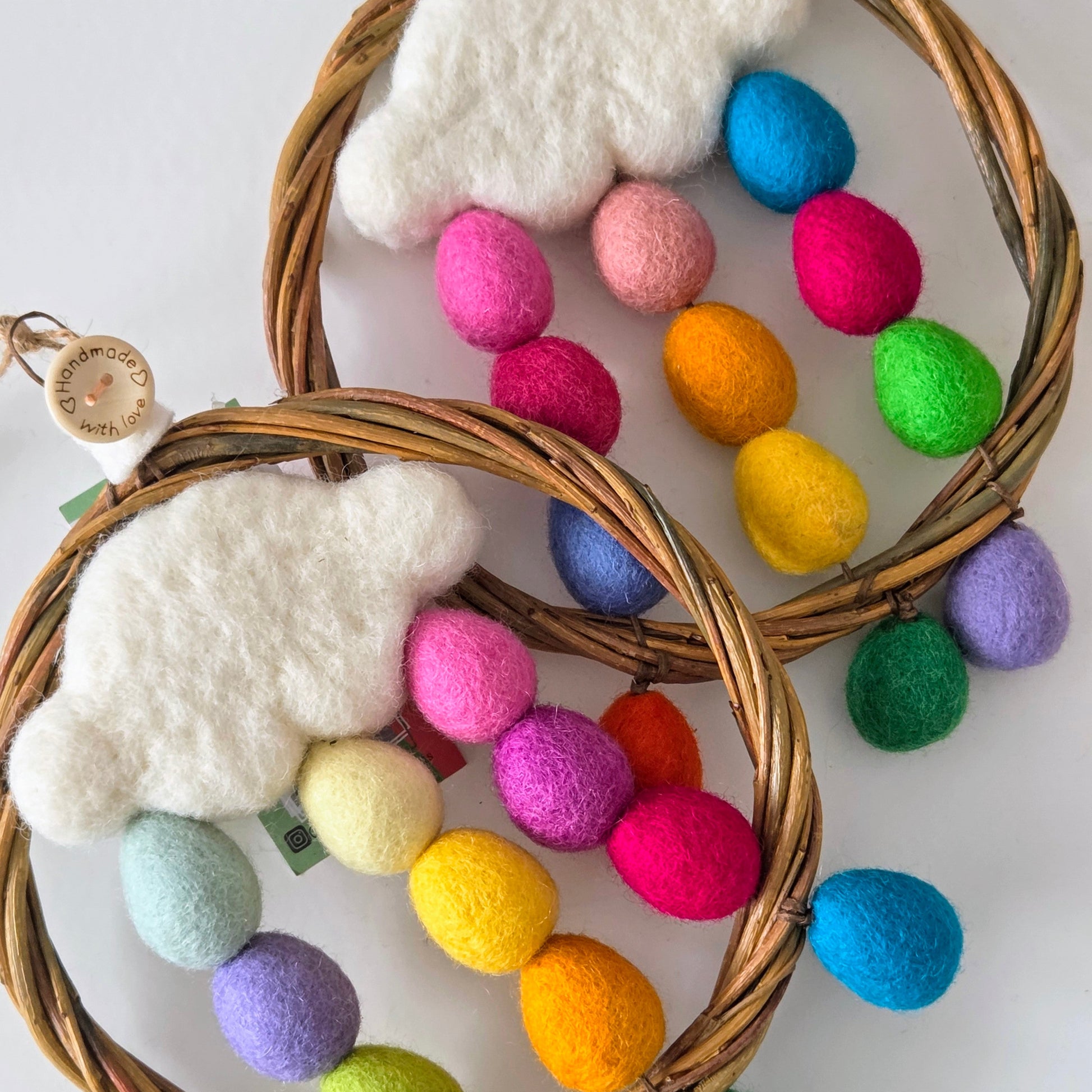 Decorative wreaths with colorful felt balls and white cloud decorations on a white background