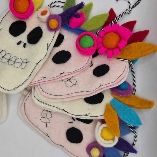 Colorful handmade decorations resembling sugar skulls with floral elements on a white background