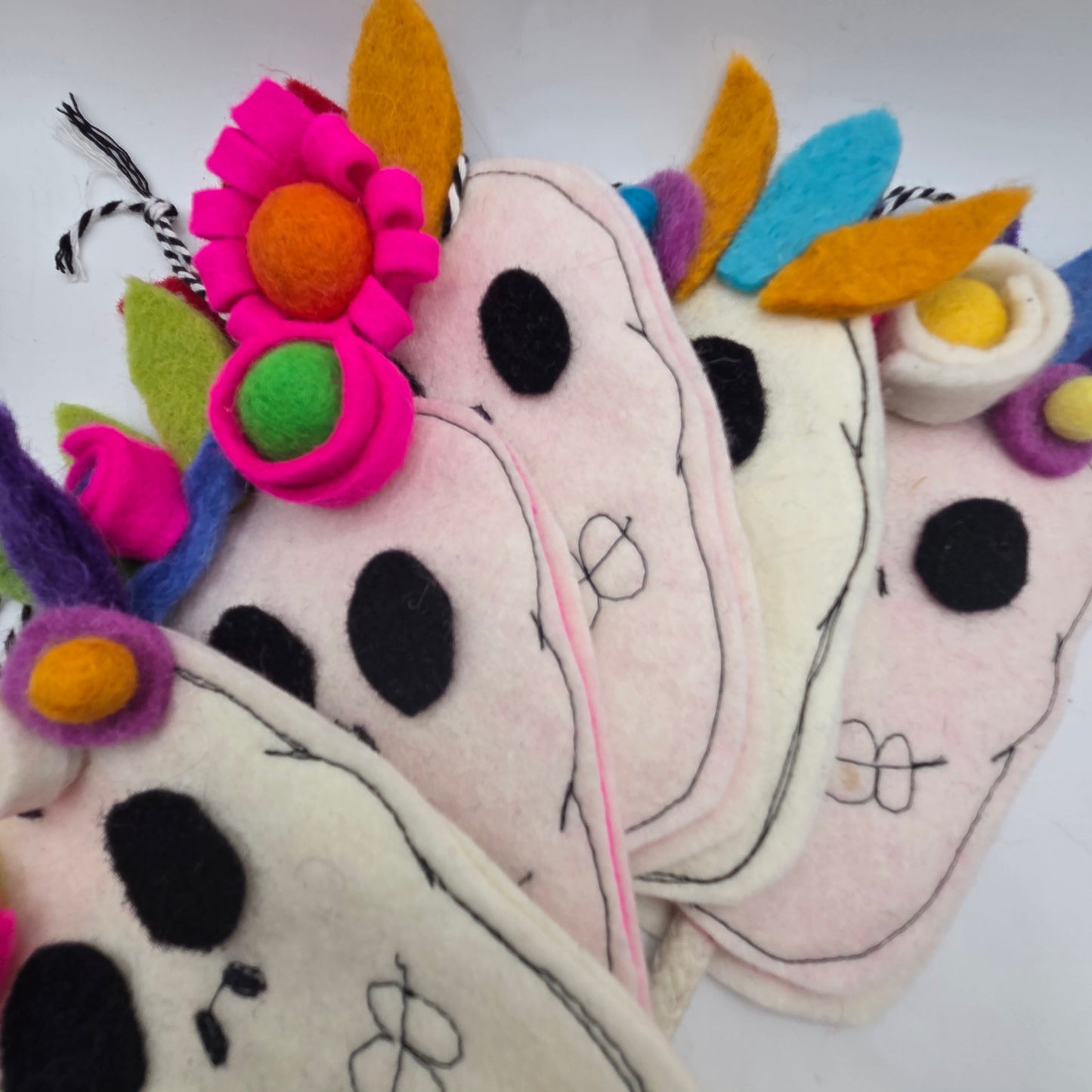 Colorful felt cow toys with floral decorations on a white background
