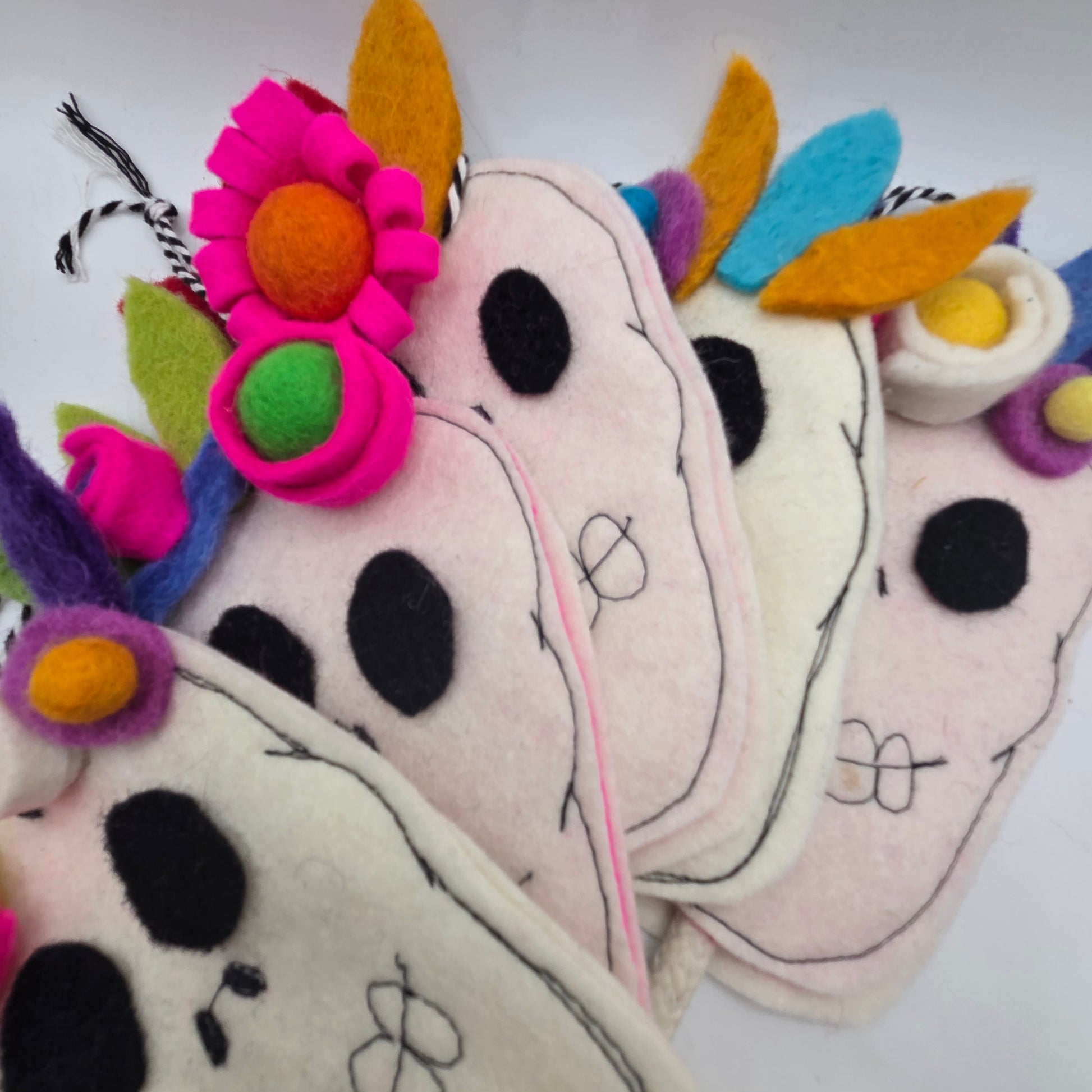 Colorful felt cow toys with floral decorations on a white background