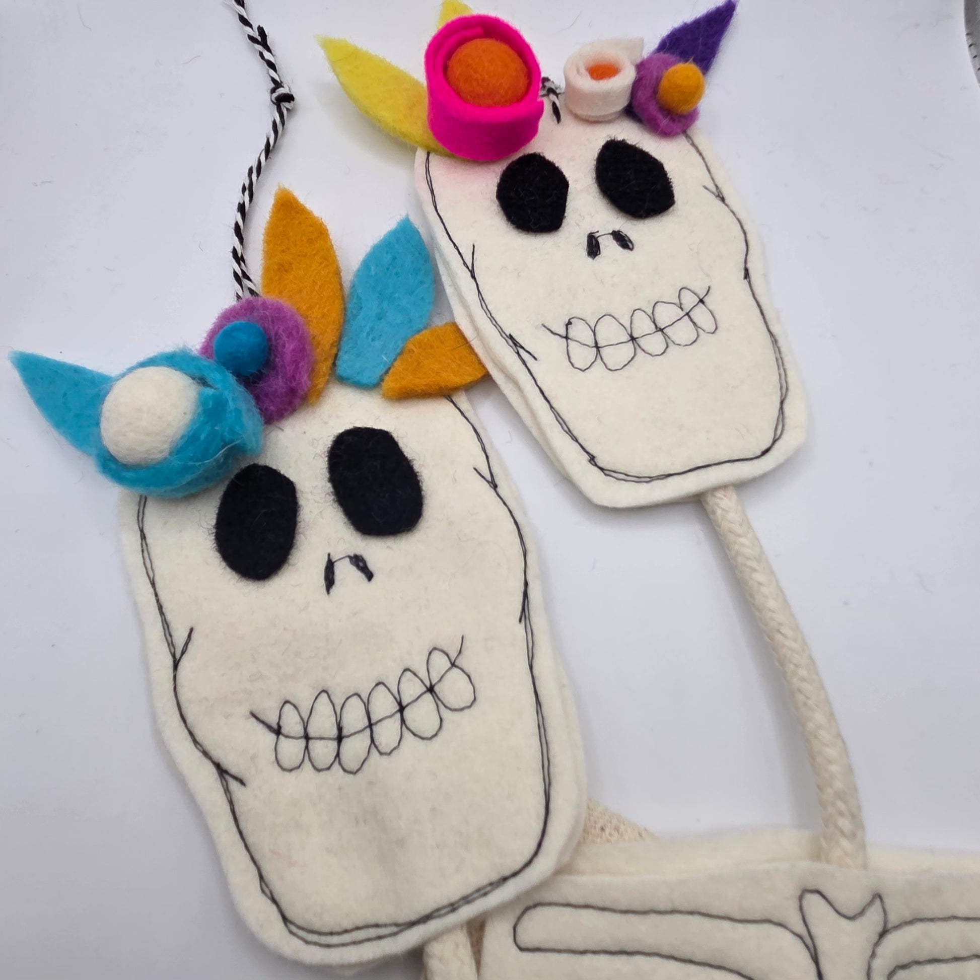 Two colorful skull-shaped masks with decorative elements on a white background