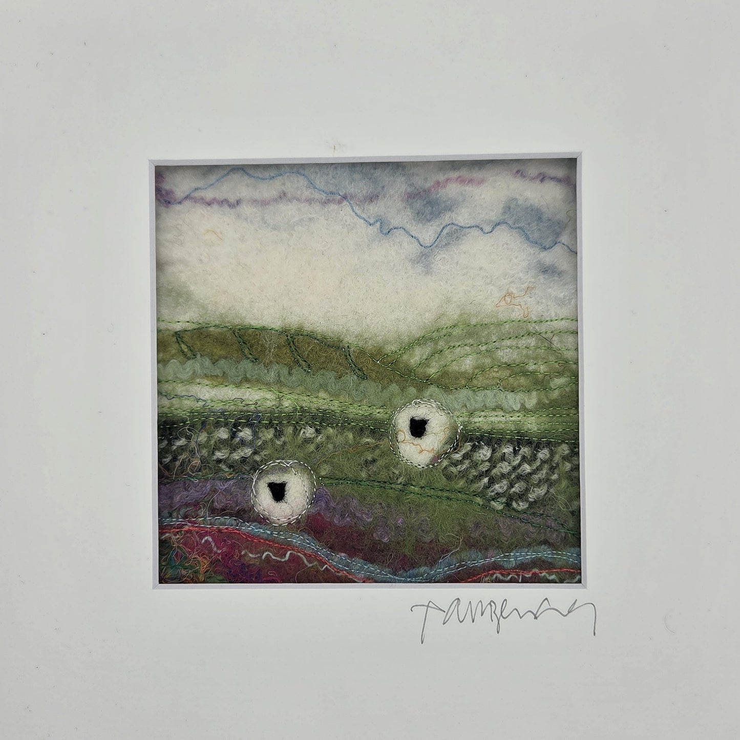 Textile art piece with landscape design on a white background