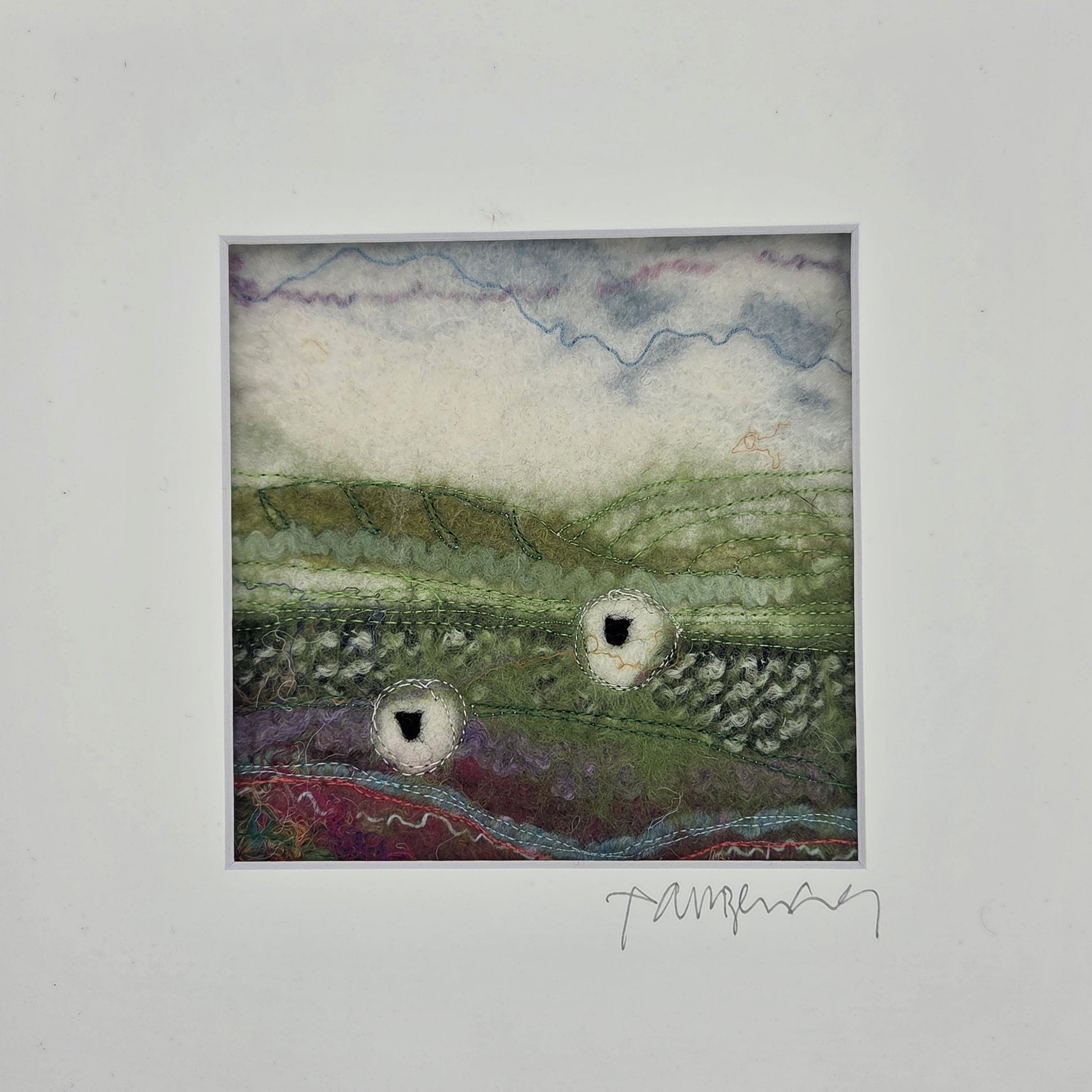 Textile art piece with landscape design on a white background