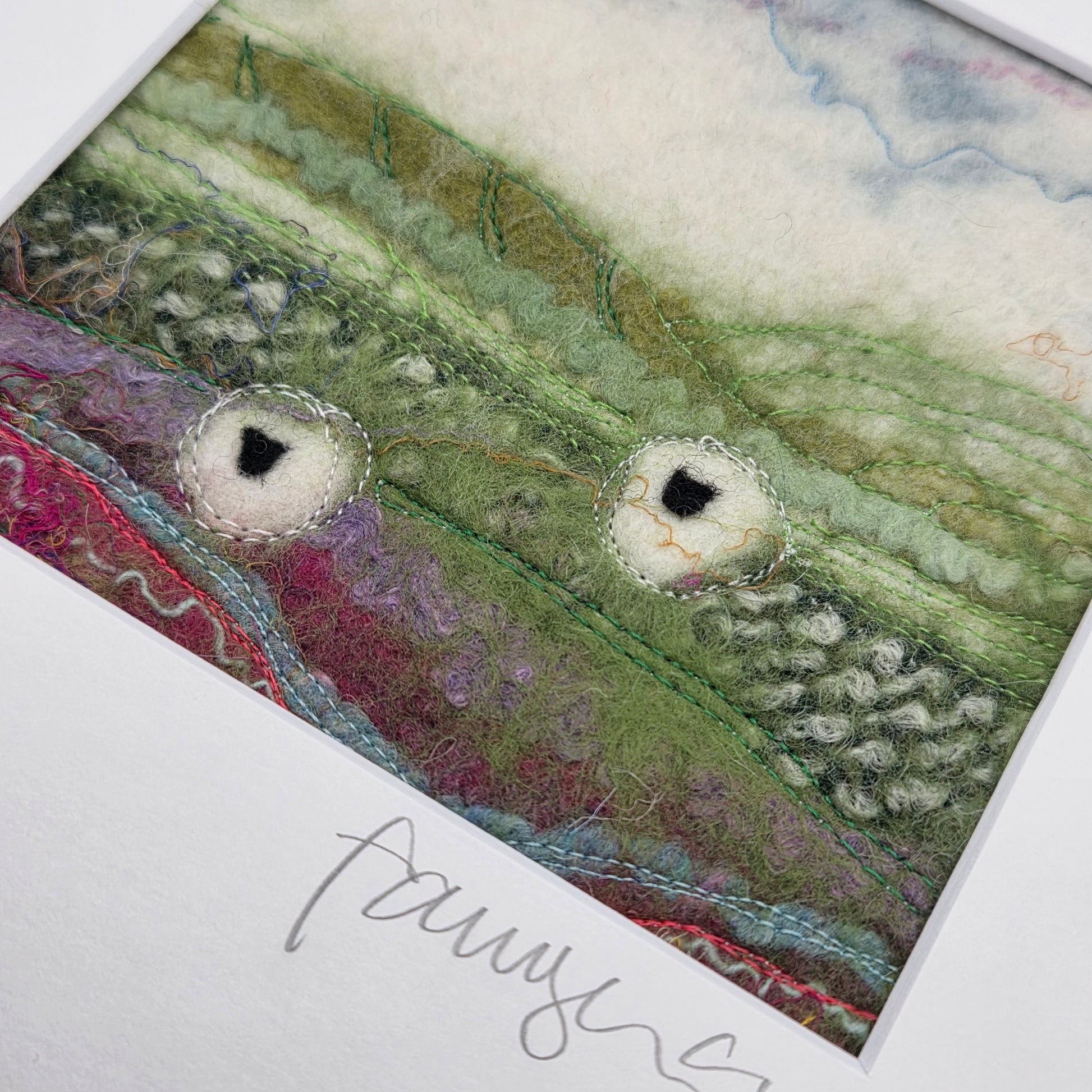 Textile art piece with green, purple, and red colors on a white background