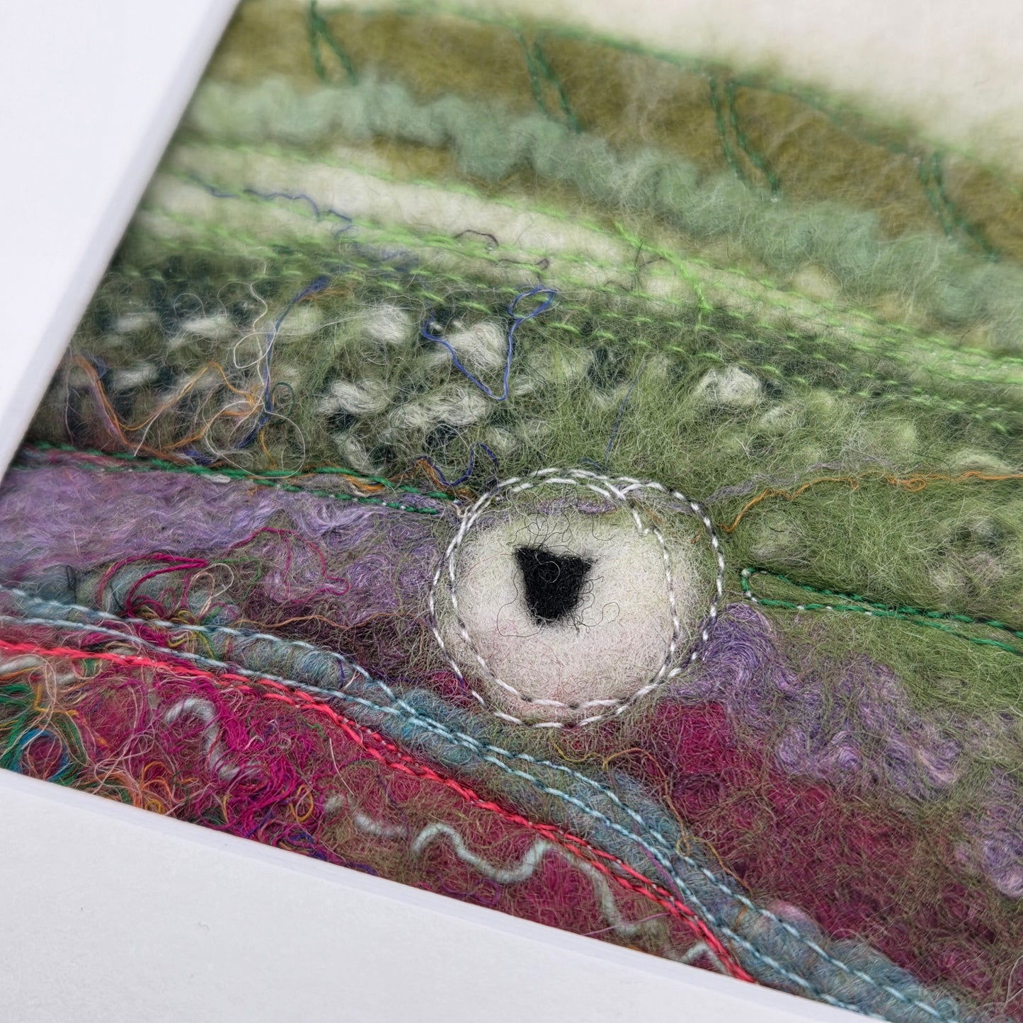 Close-up of a textured fabric with colorful patterns and a circular cutout.