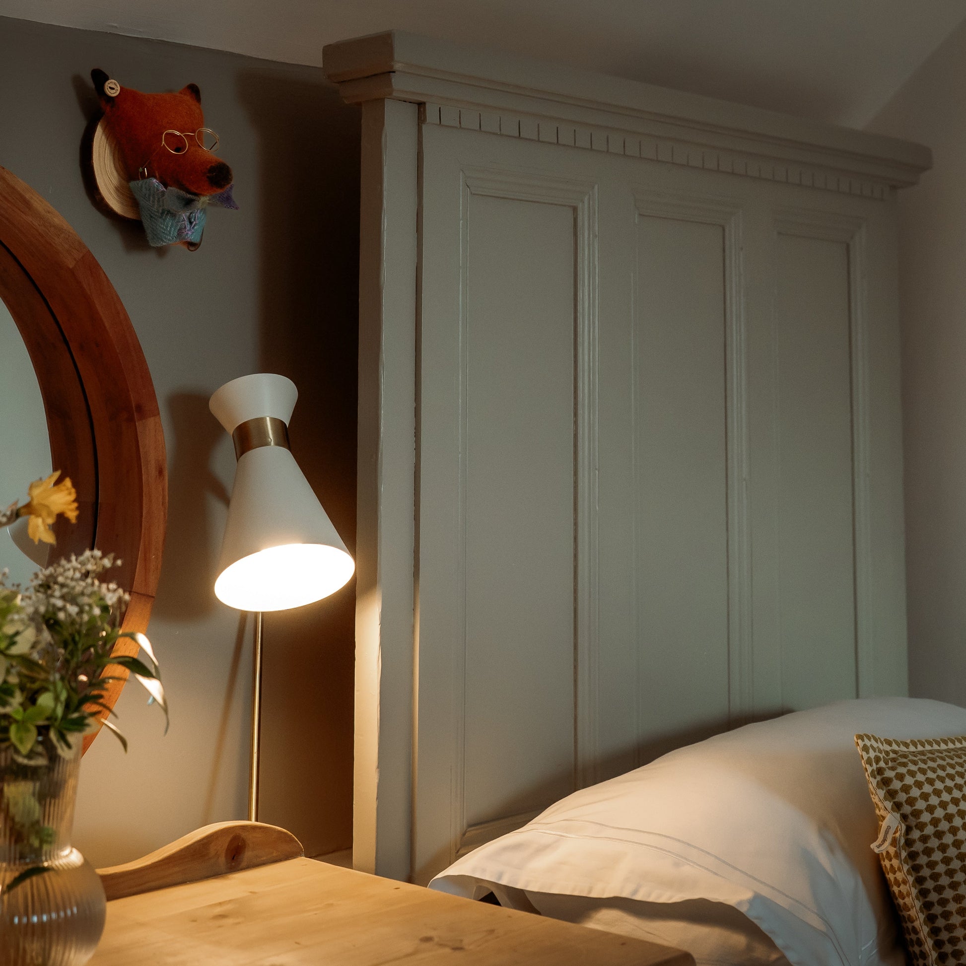 Bedroom with wooden wardrobe, lamp, and decorative items on a neutral background