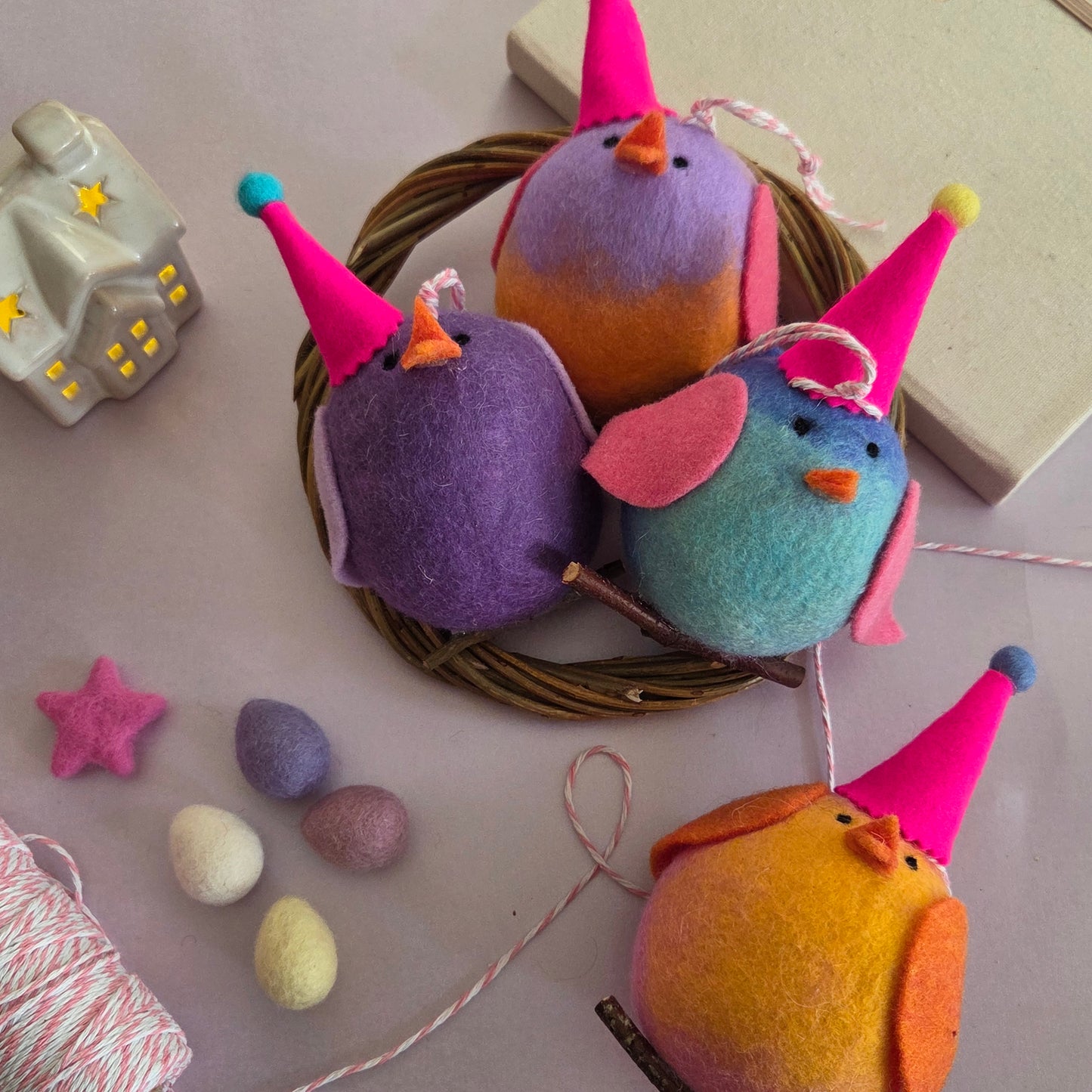 Colorful bird-shaped decorations with party hats on a neutral background