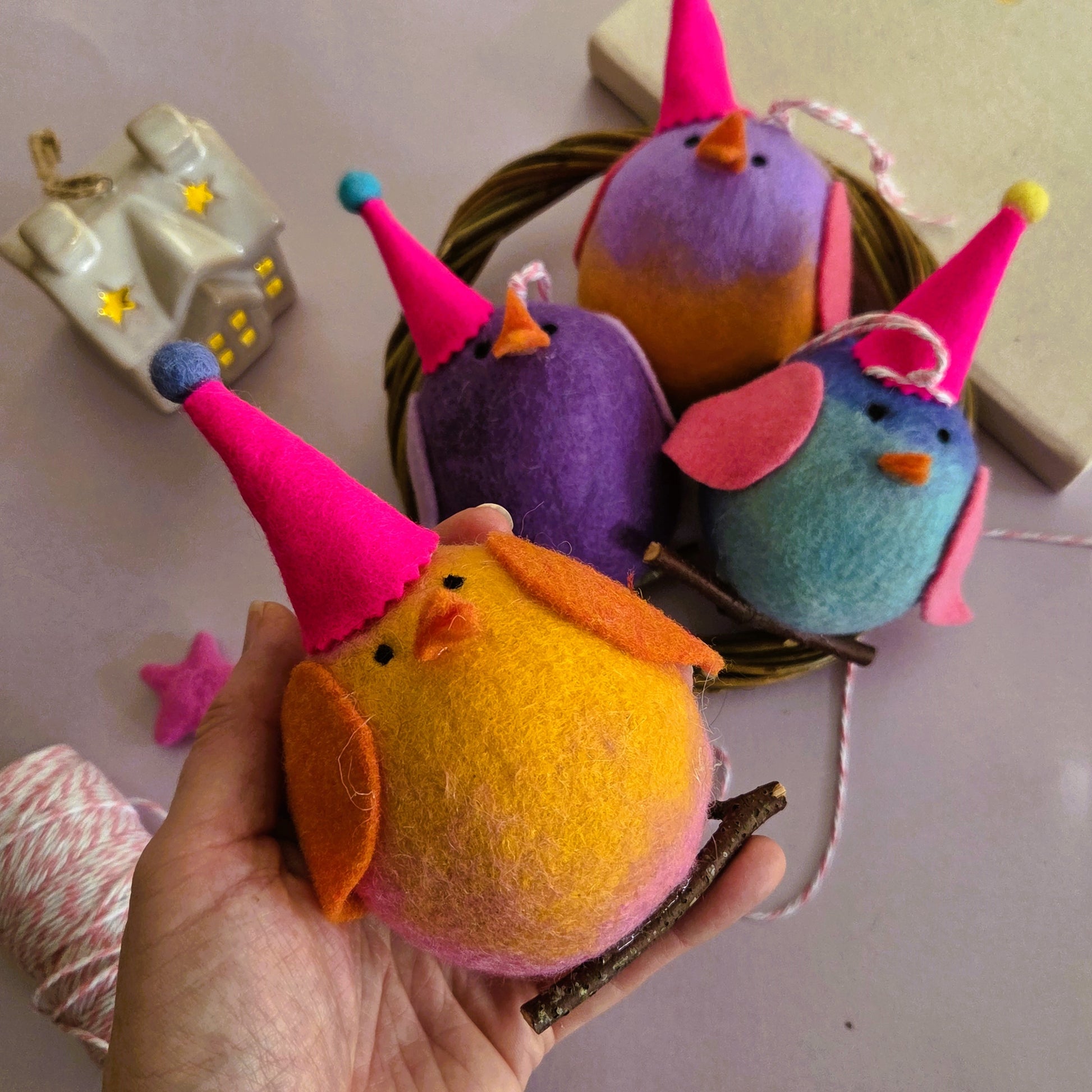 Colorful felt birds with party hats on a white surface