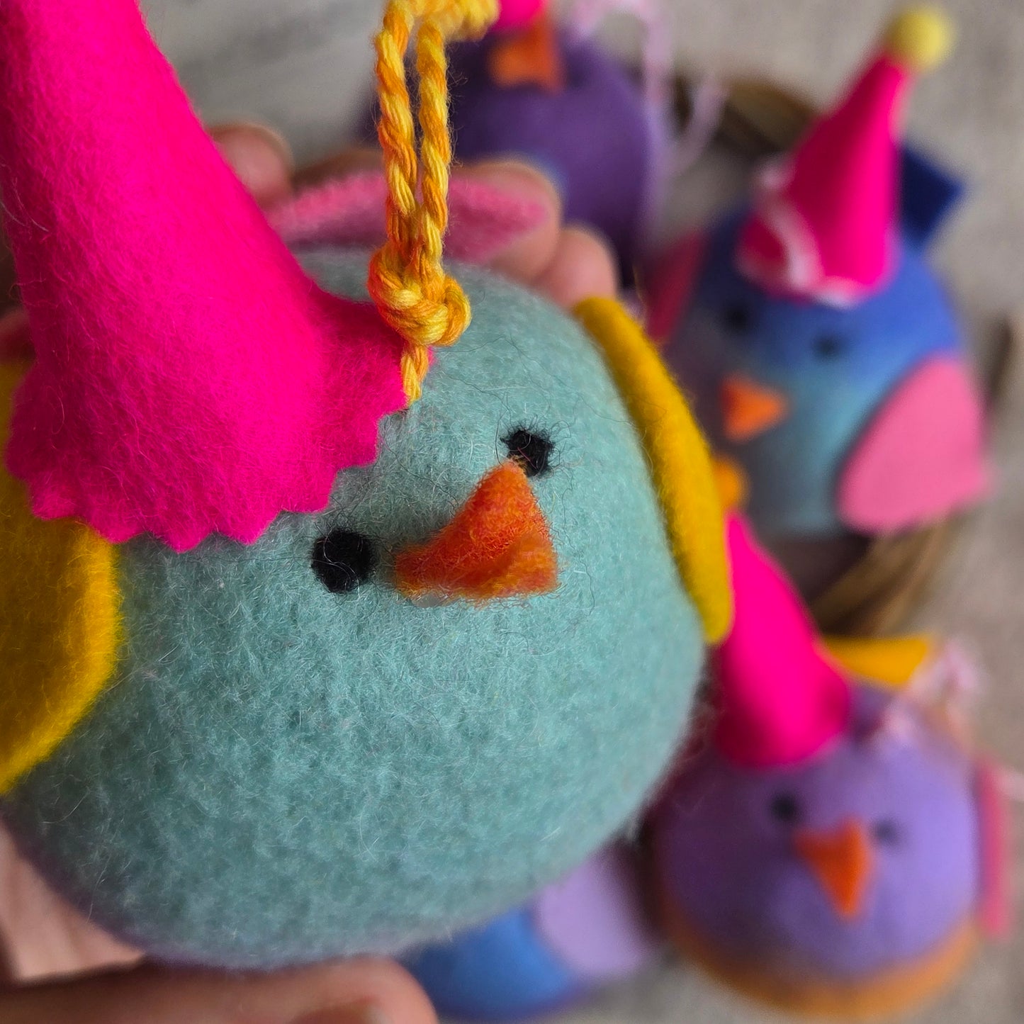 Colorful felt toys resembling animals held by a person.