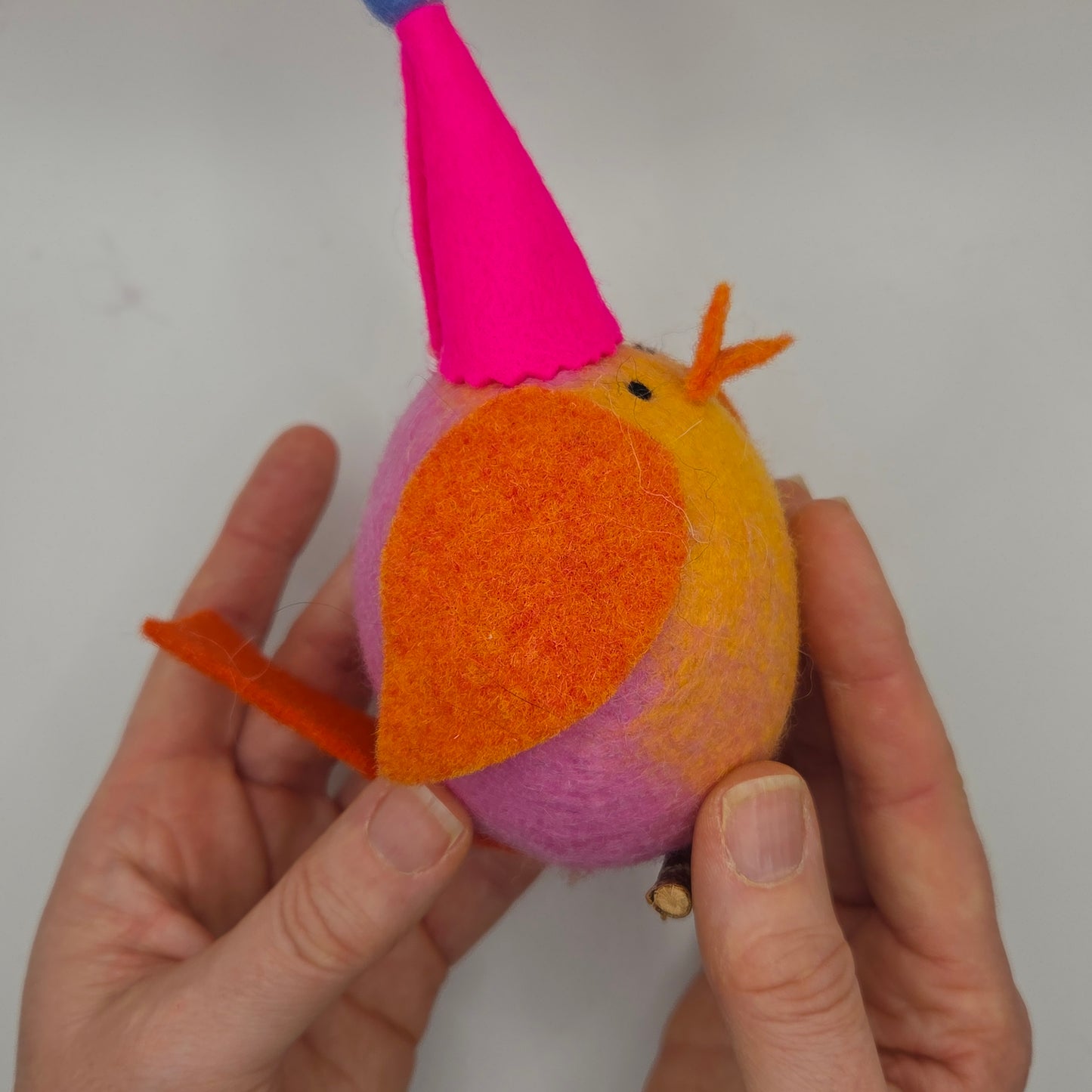 Hand holding a colorful bird-shaped toy against a plain background