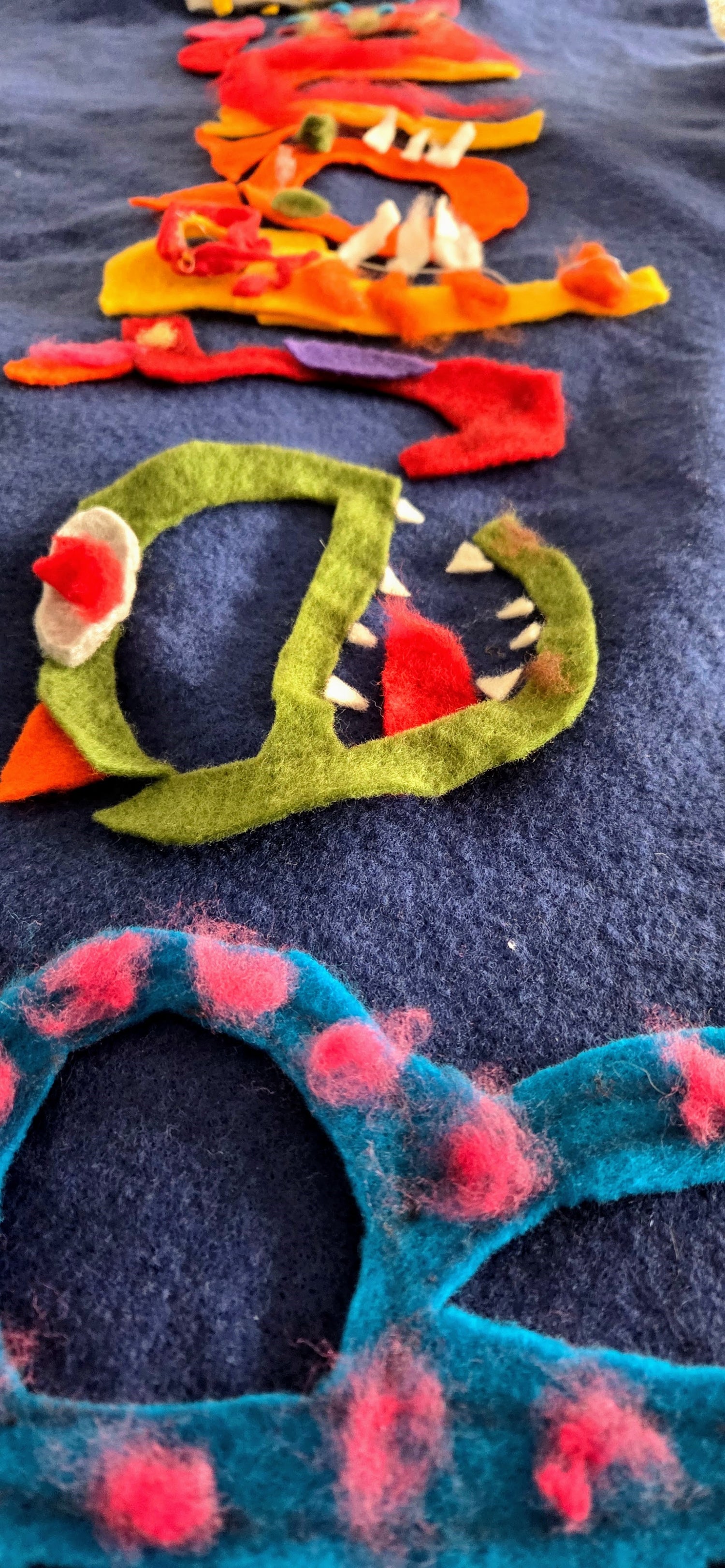 Colorful felted animal toys on a dark surface