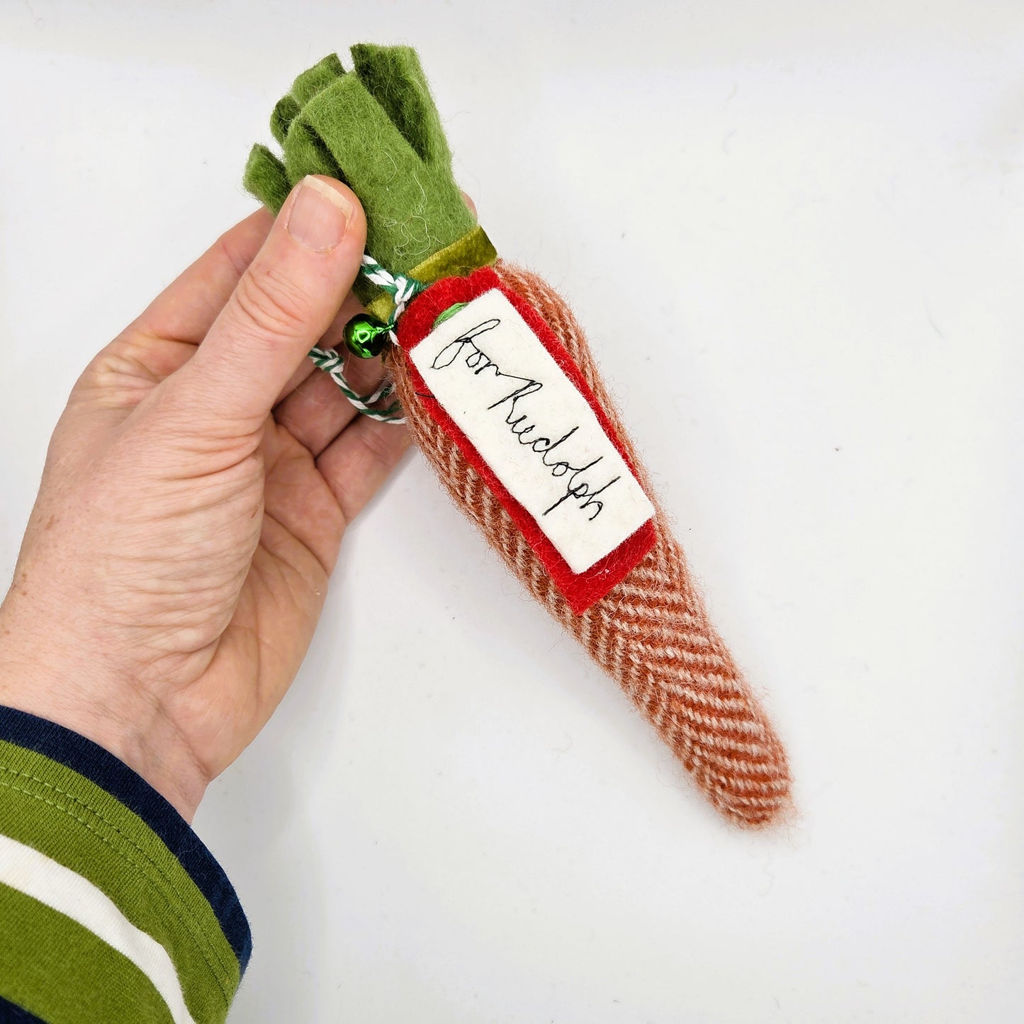 Hand holding a small Christmas-themed keychain with a tag labeled 'for Rudolph' on a white background.