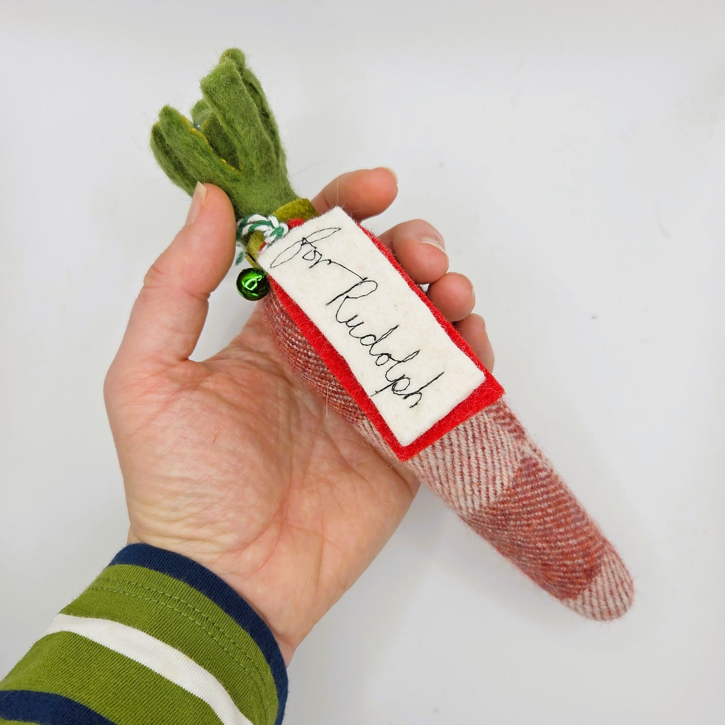 Hand holding a small Christmas decoration with a label on a white background